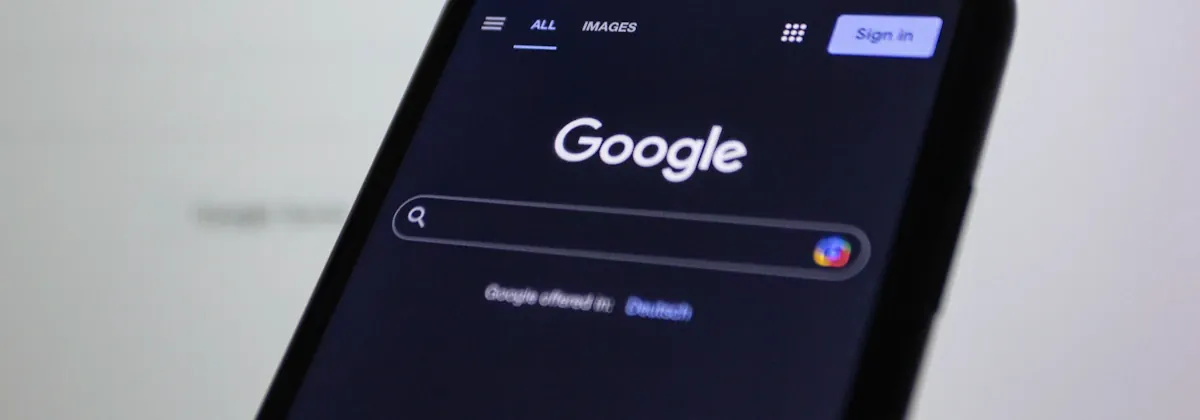 Smartphone-Nahaufnahme mit dem Google-Logo im Hintergrund – die KI-Suche entscheidet zunehmend, welche lokalen Betriebe oberhalb der klassischen Trefferliste zitiert werden